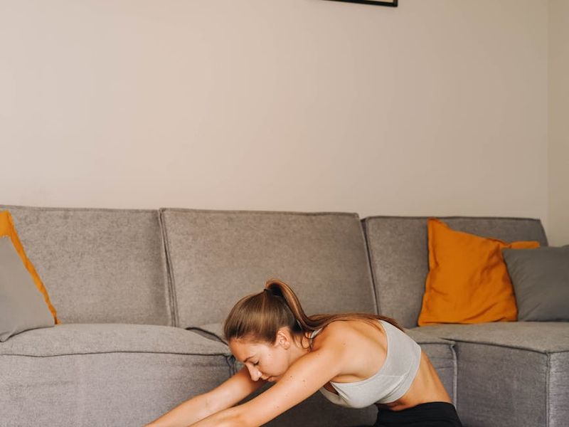 Woman performing a focused stretching routine on a mat.